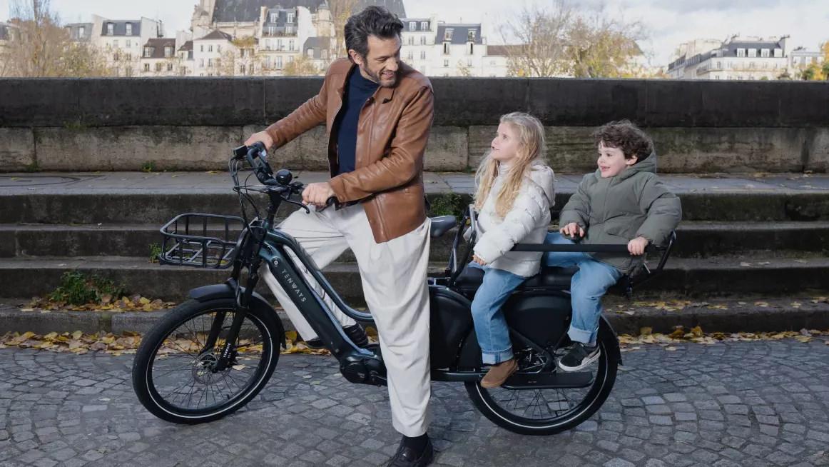 Un père et ses enfants sur un vélo cargo électrique